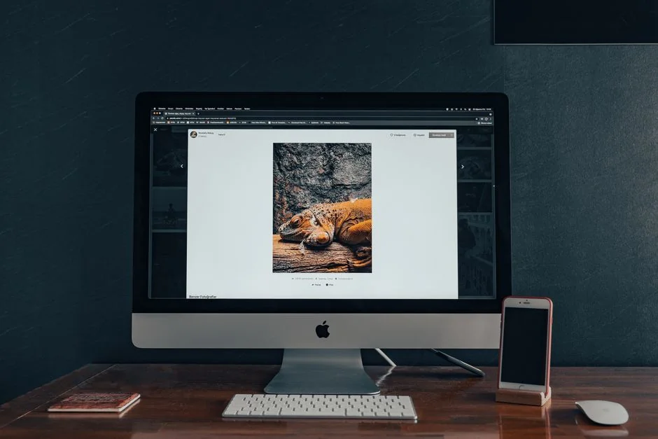 A sleek computer monitor shows web design work, highlighting creative visuals in a workspace setting.